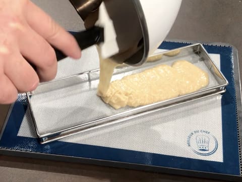 La pâte à biscuit financier est versée dans le cadre à tarte rectangulaire qui est posé sur un tapis de cuisson silicone
