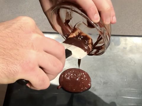 Le chocolat fondu est versé sur le verso d'une plaque à pâtisserie