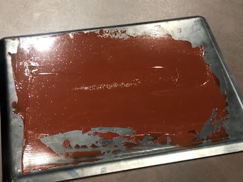 Le chocolat fondu est étalé sur la plaque à pâtisserie