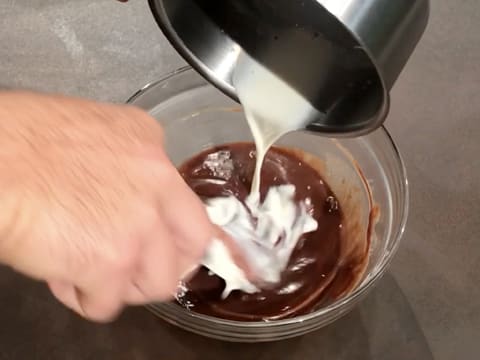 Le restant de lait est versé dans le chocolat au lait fondu tout en mélangeant avec la spatule maryse