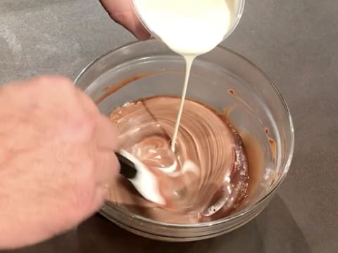 La crème liquide est incorporée dans la préparation chocolatée avec la spatule maryse