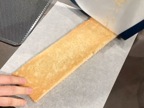 Pose du biscuit financier sur une feuille de papier sulfurisé et retrait du tapis de cuisson silicone