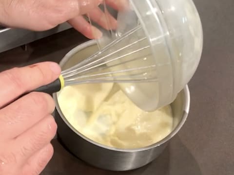 La préparation à base de lait, jaunes d'œufs et sucre, est transvasée dans la casserole