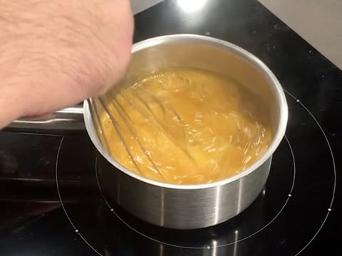 Cuisson de la préparation à base de purées de fruits dans la casserole tout en mélangeant au fouet