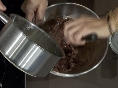 Le sirop contenu dans la casserole est versé dans le mélange chocolaté contenu dans le cul de poule
