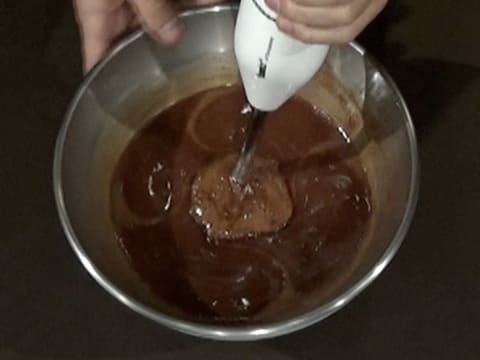 Le glaçage chocolat obtenu dans le cul de poule, est mixé à l'aide du mixeur plongeant
