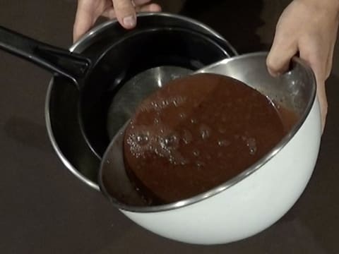 Le glaçage chocolat est filtré dans une passoire fine au-dessus d'un cul de poule