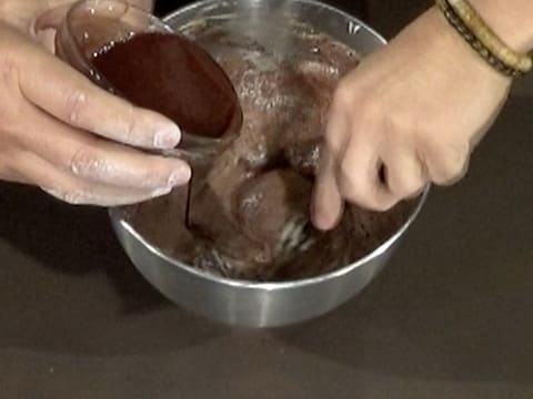 Le chocolat et le beurre fondus sont versés sur la préparation crémeuse, dans la cuve du batteur, tout en étant incorporés avec la spatule maryse