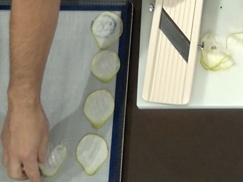 Les tranches de poire sont disposées sur un tapis de cuisson en silicone qui est posé sur une plaque à pâtisserie