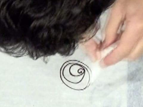 Une spirale de chocolat noir est dessinée au cornet décor sur une feuille de papier sulfurisé