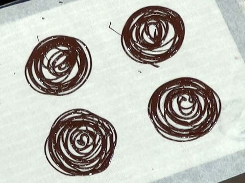 Quatre spirales de chocolat noir ont été formées sur la feuille de papier sulfurisé
