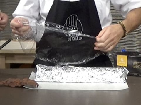 La feuille de papier film est déposée sur l'aluminium qui recouvre le moule à bûche