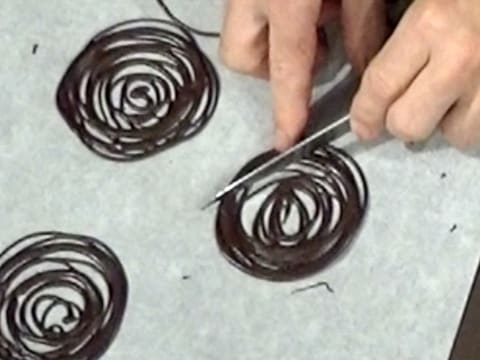 Une petite partie d'un spirale en chocolat noir est coupée au couteau