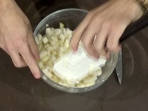 Les cubes de poire sont mélangés à l'aide de la spatule type maryse, dans le saladier en verre