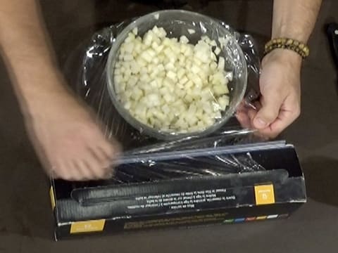 Le saladier en verre contenant les cubes de poire est filmé avec une feuille de papier film