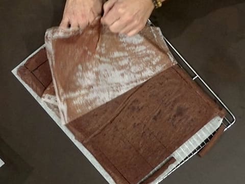 La feuille de cuisson du biscuit chocolat est retirée, et laisse entrevoir le biscuit