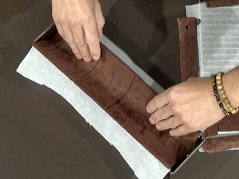 Le biscuit chocolat est moulé à l'intérieur du moule à bûche chemisé de la feuille de papier sulfurisé