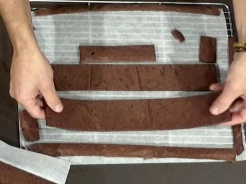 Vue de dessus des bandes de biscuit chocolat sur la grille à pâtisserie recouverte d'une feuille de papier sulfurisé