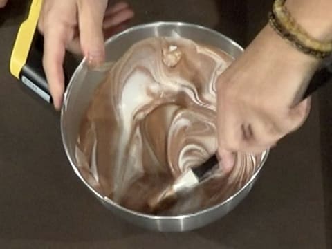 La préparation chocolatée et mélangée avec la crème fouettée à l'aide de la spatule type maryse, dans la cuve du batteur