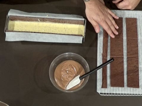 Vue de dessus du moule à bûche, de la mousse chocolat et des bandes de biscuit chocolat