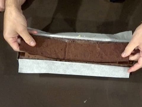 Deux bandes de biscuit chocolat sont placées dans le moule à bûche chemisé, sur la mousse chocolat