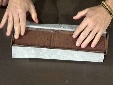 Les deux bandes de biscuit chocolat sont placées dans le moule à bûche chemisé, sur la mousse chocolat