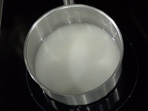 Cuisson du mélange eau et sucre en poudre dans la casserole sur la plaque de cuisson
