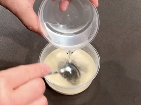 L'eau d'hydratation est versée sur la gélatine en poudre dans un petit récipient, tout en étant mélangées avec une petite cuillère