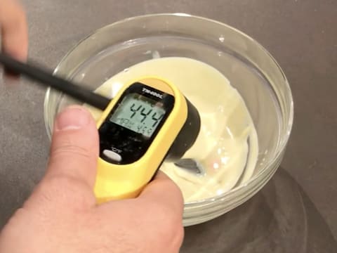 À L'aide d'un thermomètre à visée laser, prise de la température du chocolat blanc fondu dans le bol, qui titre 44,4°C