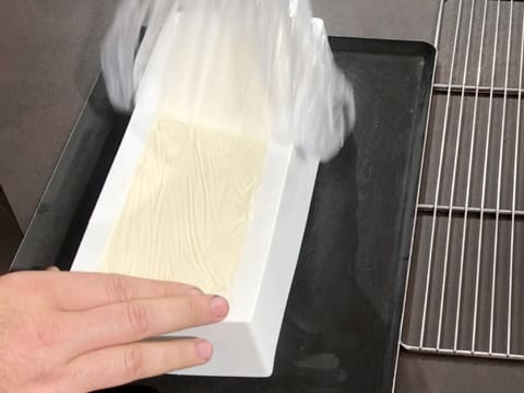 La feuille de papier film qui recouvre le moule à bûche en silicone, est retirée