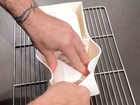 Le moule à bûche en silicone est retiré, et le démoulage de la bûche se fait sur une grille à pâtisserie