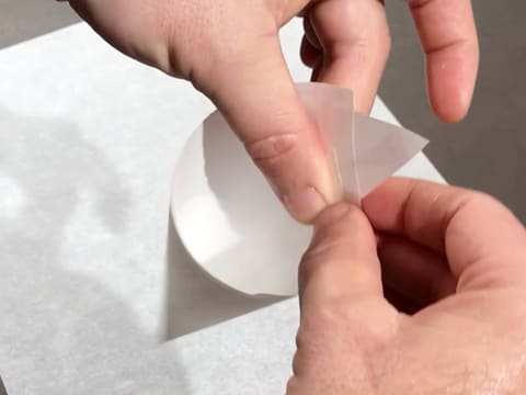 Une feuille de papier sulfurisé est enroulée pour réaliser un cornet décor