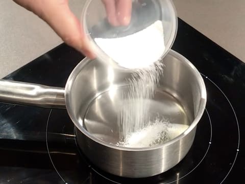 Le Sorbitol en poudre est versé dans une casserole contenant le sirop de glucose et le miel