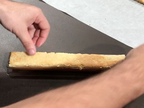 La bande de biscuit aux pignons de pin est posée sur la compotine de pamplemousse, dans le moule insert à bûche