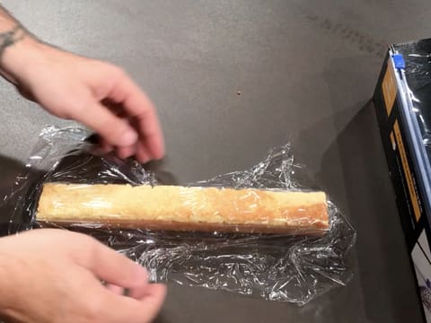 Le biscuit aux pignons de pin et le moule insert à bûche sont filmés au contact avec une feuille de papier film