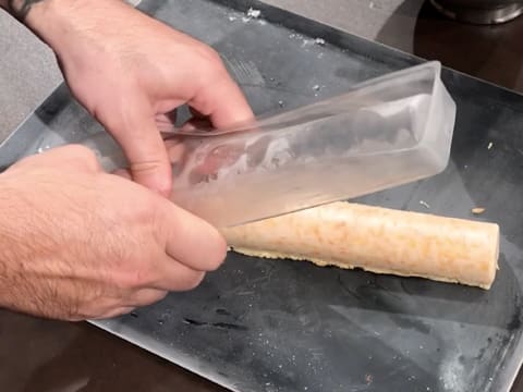 Le moule insert à bûche est retiré, et l'insert est démoulé sur une plaque à pâtisserie, posée sur le plan de travail