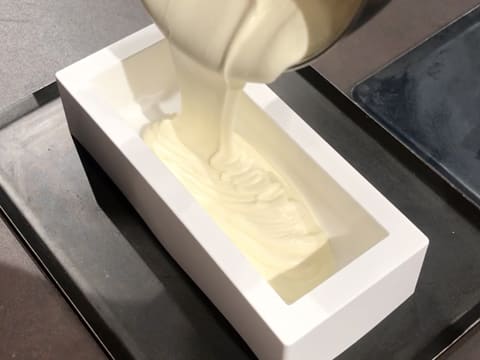 La mousse Champagne est versée dans le moule à bûche en silicone