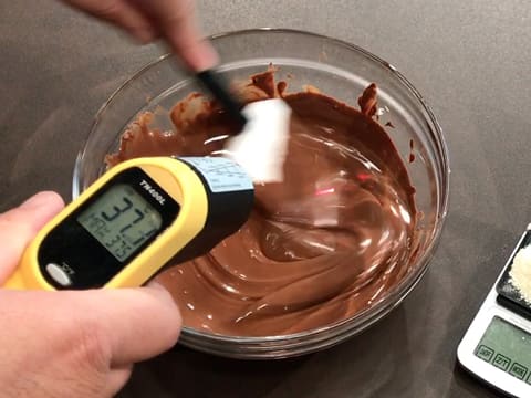 Prise de la température du chocolat au lait fondu qui est mélangé avec une spatule type maryse