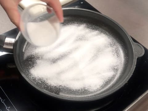 Le sucre en poudre est parsemé sur toute la surface de la poêle qui est placée sur une plaque de cuisson