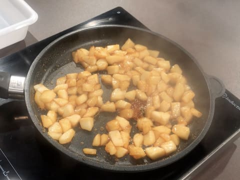 Les cubes de poires sont enrobés de caramel et sont en train de cuire dans la poêle