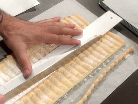 La bande de biscuit à la cuillère est coupée pour former une largeur de 5 cm à l'aide du couteau-scie à génoise