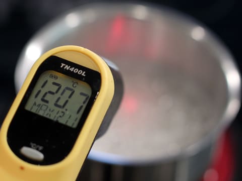 Prise de la température du sirop qui bout dans la casserole, à l'aide d'un thermomètre à visée laser qui affiche 120,7°C