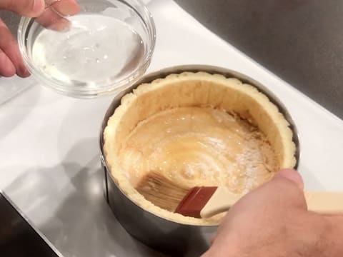 Les bandes et le disque de biscuit à la cuillère sont punchés avec du sirop de punchage à l'aide d'un pinceau pâtissier