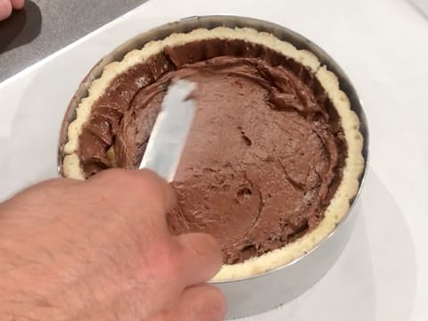 La surface de la mousse au chocolat est lissée avec la petite spatule coudée