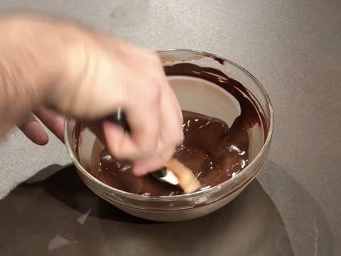 Le chocolat noir fondu est mélangé dans le saladier en verre, avec la spatule maryse