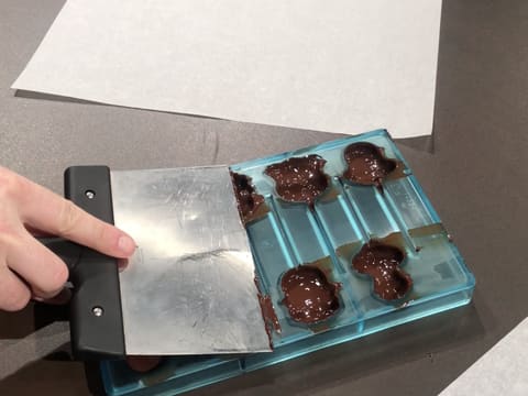 La surface du moule est arasée avec la spatule à chocolat