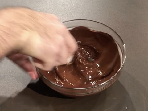 Le chocolat noir fondu est mélangé dans le saladier en verre, avec la spatule maryse