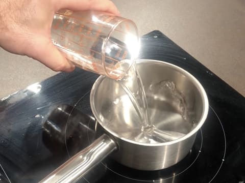 L'eau est versée dans une casserole qui est posée sur une plaque de cuisson