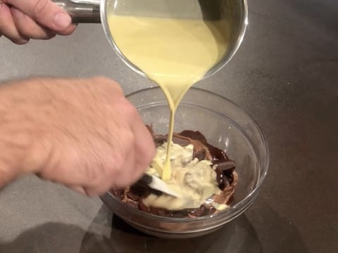 Le mélange de purée de fruit de la passion et de crème est versé sur les fèves de chocolat au lait et de chocolat noir partiellement fondues
