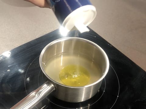 Ajout d'une pincée de sel dans la casserole qui contient l'eau, le jus de yuzu et l'huile d'olive